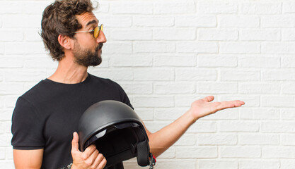 young man feeling happy and smiling casually, looking to an object or concept held on the hand on...