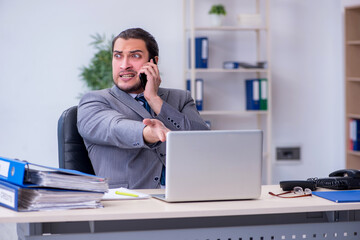 Young male employee unhappy with excessive work in the office