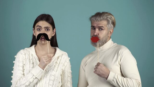 Funny couple change gender. Funny and Crazy Idea. Humorous video. Human emotions, youth, love and lifestyle. Stereotypical gender roles. Couple with paper mustache and female red lips.