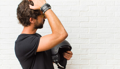 young man feeling clueless and confused, thinking a solution, with hand on hip and other on head,...