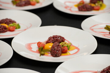 tartare meat with egg, cucumber, tomato and avocado closeup on a white plate.