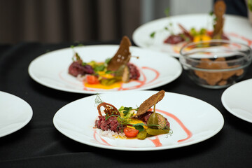 tartare meat with egg, cucumber, tomato and avocado closeup on a white plate.