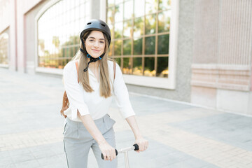 Portrait of a female employee using a helmet and riding a scooter