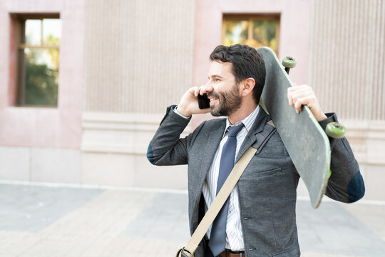 Male worker talking on his cellphone and holding his skateboard - Powered by Adobe