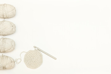 skeins of gray cotton yarn on a light background and a crocheted blank for the product. Top view with space