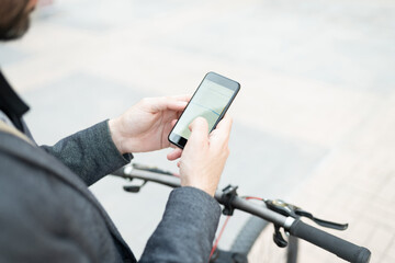 Man in his 30s with a bycicle looking a the gps app on his smartphone
