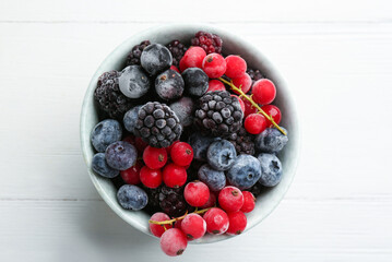 Mix of tasty frozen berries on white wooden table, top view