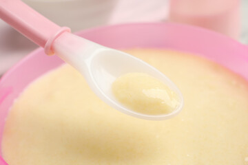 Obraz na płótnie Canvas Spoon of healthy baby food over bowl, closeup