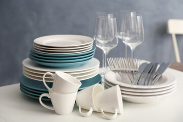 Set of clean dishware, cutlery and wineglasses on white table indoors
