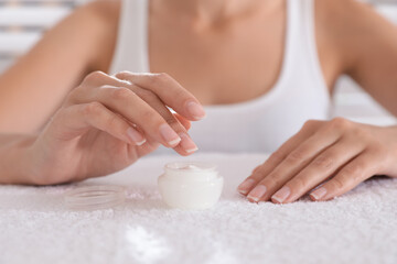 Naklejka premium Woman taking cream from jar on white towel, closeup