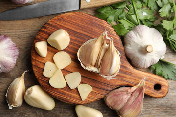 Flat lay composition with fresh sliced and whole garlic on wooden table. Organic product