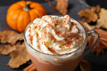 Delicious pumpkin latte with whipped cream on table, closeup