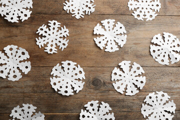 Many paper snowflakes on wooden background, flat lay