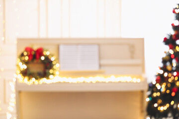 Blurred view of white piano with fairy lights indoors. Christmas music