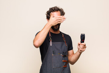 young man covering face with both hands saying no to the camera! refusing pictures or forbidding...