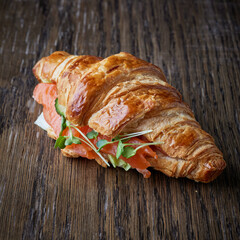 Fresh croissant with salmon and greens