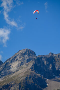 Paraplaners in tandem gliding in blue sky and Alpine mountains on paraplane