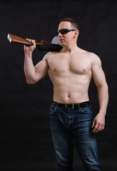 Mature man in sunglasses and naked torso with tommy gun