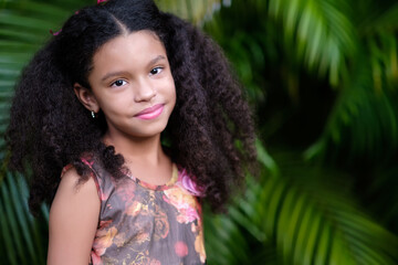 Portrait of a cute multiracial small girl with a green vegetation background