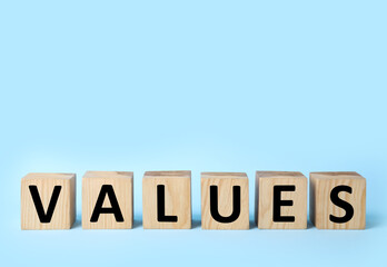 Wooden cubes with word VALUES on light blue background