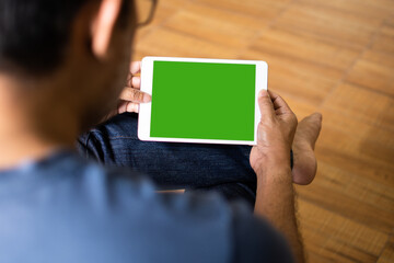 Closeup, People using the tablet device home. Men sitting relaxed and holding a tablet green blank screen for design and text in the living room on weekends, Moke up, Clipping path. blurred background