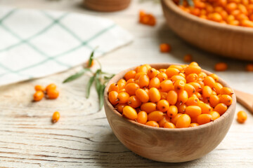 Fresh ripe sea buckthorn in bowl on white wooden table. Space for text