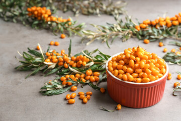 Fresh ripe sea buckthorn in bowl on grey table