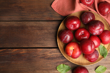 Fototapeta na wymiar Delicious ripe plums on wooden table, flat lay. Space for text