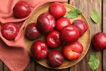 Delicious ripe plums on wooden table, flat lay