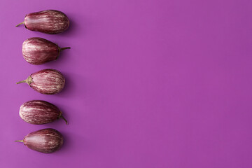 Raw ripe eggplants on purple background, flat lay. Space for text