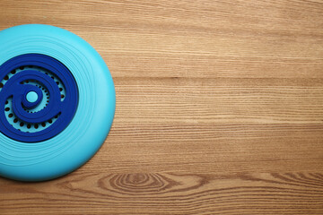 Blue plastic frisbee disk on wooden background, top view. Space for text