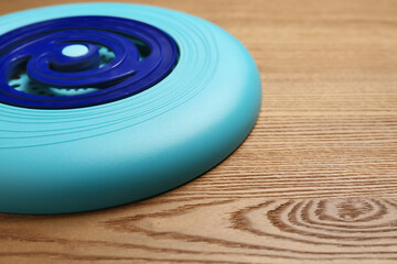 Fototapeta na wymiar Blue plastic frisbee disk on wooden background, closeup. Space for text