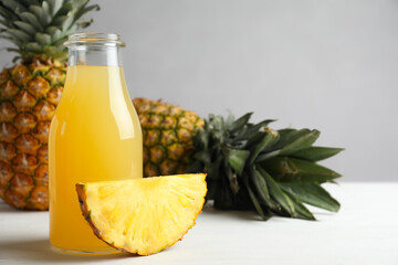 Delicious pineapple juice and fresh fruit on white wooden table