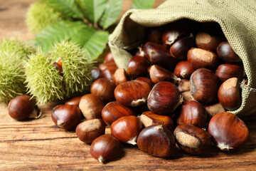 Fresh sweet edible chestnuts on wooden table, closeup