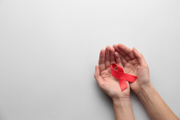 Woman holding red awareness ribbon on white background, top view with space for text. World AIDS disease day