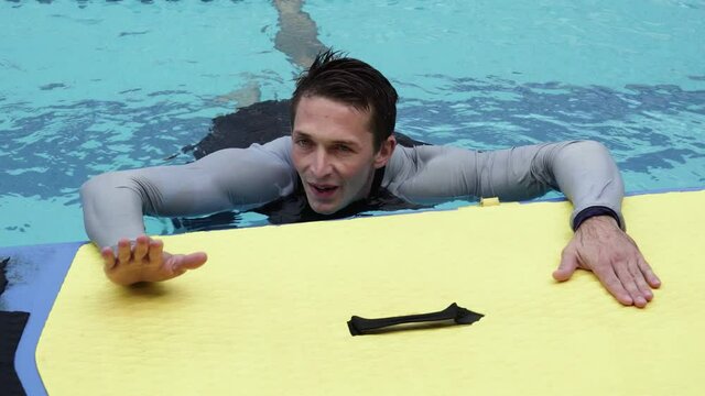 Professional sportsman Stands Up on yellow sup board in swimming pool