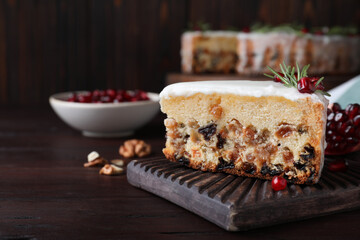 Piece of traditional homemade Christmas cake and fresh pomegranate on wooden table, closeup. Space for text