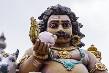 Kadirampura, Karnataka, India - November 4, 2013: Sri Murugan Temple. Colorful facial closeup of Dwarapalaka against silver sky.