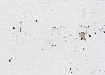 A cracked white thing on the wall.The texture is detached under the influence of the weather paint and plaster.Background with large cracks.