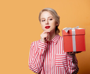 girl in shirt in red strip with gift on yellow background