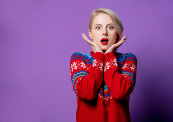 Beautiful woman in Christmas sweater on purple background