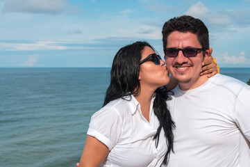 Woman kissing her boyfriend on the cheek at the beach