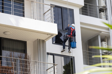 A man window cleaner climbing on the wall to cleaning window  on a high building. 