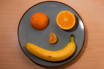 Funny face made up of a banana, orange and mandarin