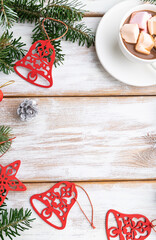 Christmas or New Year frame composition. Decorations, red stars, bells, cones, fir and spruce branches, on a white wooden background. Top view, copy space.