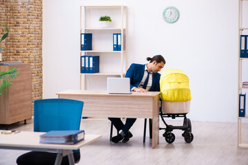 Young male employee looking after kid at workplace