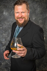Solid smiling bearded man in suit with glass of whisky