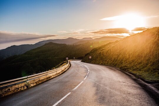 Diminishing Perspective Of Empty Road Amidst Mountains Against Sky During Sunset