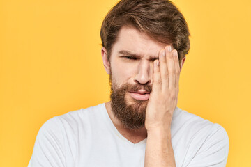 Man in white t-shirt emotions studio gestures with hands displeased facial expression yellow background