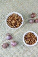 Bawang Merah Goreng or fried shallots, popular Indonesian food topping. Served on white ceramic bowl. Isolated background, copy space.